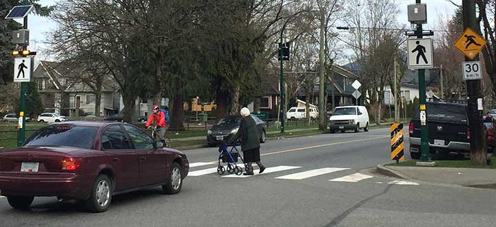 Car and cyclist stopped for pedestrian at crosswalk with flashing beacon at Victoria and Grant streets Car and cyclist stopped for pedestrian at crosswalk with flashing beacon at Victoria and Grant streets
