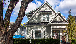 White detached single-family house with a short hedge and sidewalk in the foreground